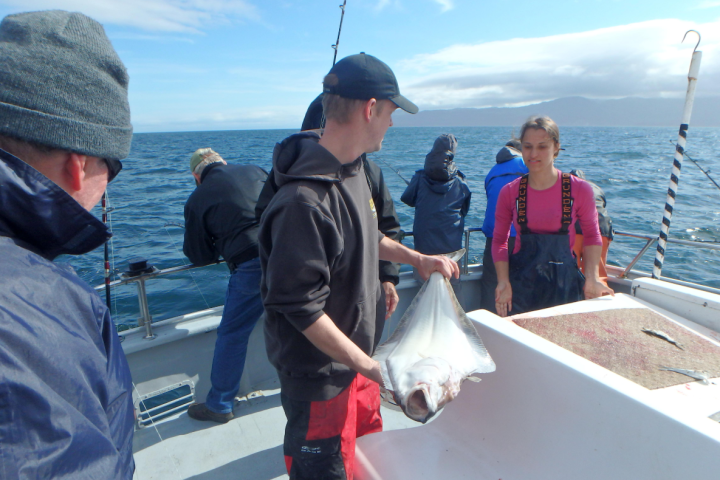 Rainbow Tours fishing staff holding a halibut on the boat